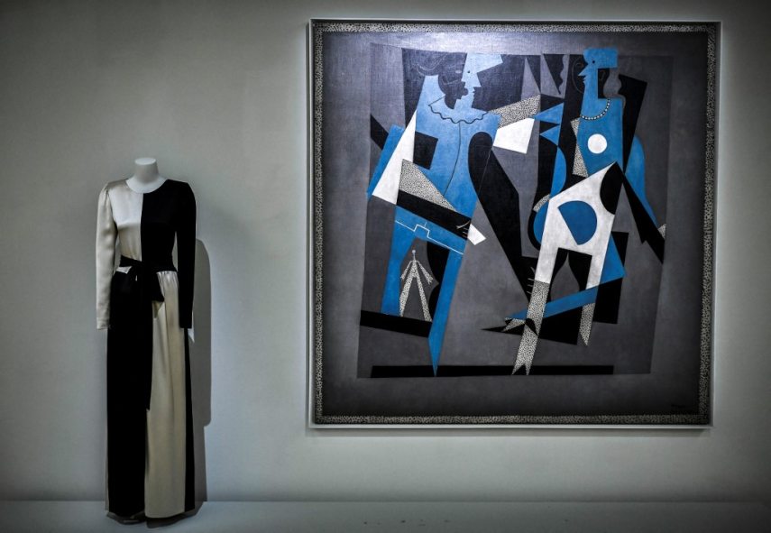 This photograph taken in Paris on January 25, 2022 shows a creation of late French designer Yves Saint-Laurent displayed next a painting entitled 'Arlequin et femme au collier' by artist Pablo Picasso at the Centre Pompidou (National Modern Art Museum) as part of the exhibitions "Yves Saint-Laurent at the museums". (Photo by STEPHANE DE SAKUTIN / AFP) / RESTRICTED TO EDITORIAL USE - MANDATORY MENTION OF THE ARTIST UPON PUBLICATION - TO ILLUSTRATE THE EVENT AS SPECIFIED IN THE CAPTION - NO ARCHIVES - NO USE AFTER MAY 16, 2022