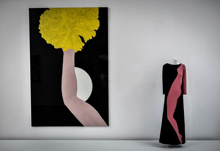 This photograph taken in Paris on January 25, 2022 shows a creation of late French designer Yves Saint-Laurent displayed next a painting entitled 'The Moon' by artist Gary Hume at the Centre Pompidou (National Modern Art Museum) as part of the exhibitions "Yves Saint-Laurent at the museums". (Photo by STEPHANE DE SAKUTIN / AFP) / RESTRICTED TO EDITORIAL USE - MANDATORY MENTION OF THE ARTIST UPON PUBLICATION - TO ILLUSTRATE THE EVENT AS SPECIFIED IN THE CAPTION - NO ARCHIVES - NO USE AFTER MAY 16, 2022
