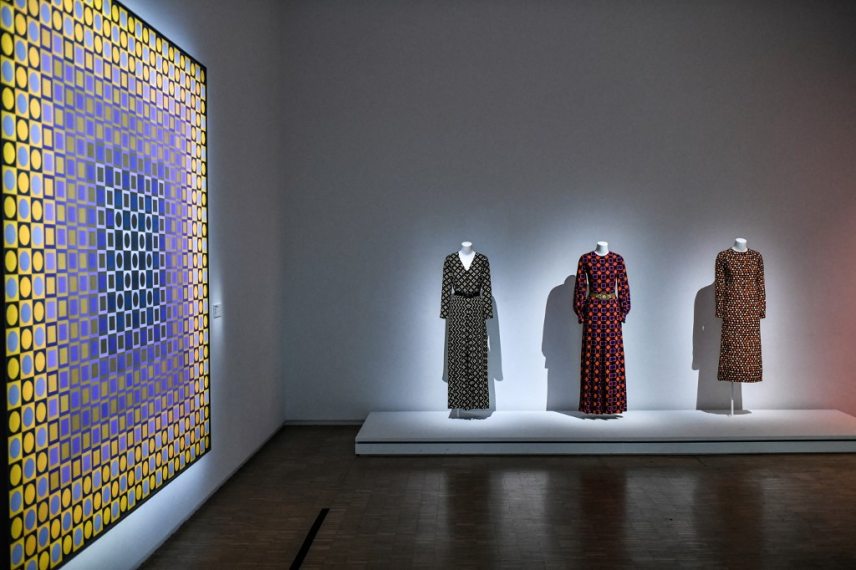 This photograph taken in Paris on January 25, 2022 shows a creation of late French designer Yves Saint-Laurent displayed next an artwork entitled  'Alom' by Hungarian-French artist Victor Vasarely at the Centre Pompidou (National Modern Art Museum) as part of the exhibitions "Yves Saint-Laurent at the museums". (Photo by STEPHANE DE SAKUTIN / AFP) / RESTRICTED TO EDITORIAL USE - MANDATORY MENTION OF THE ARTIST UPON PUBLICATION - TO ILLUSTRATE THE EVENT AS SPECIFIED IN THE CAPTION -  NO ARCHIVES - NO USE AFTER MAY 16, 2022