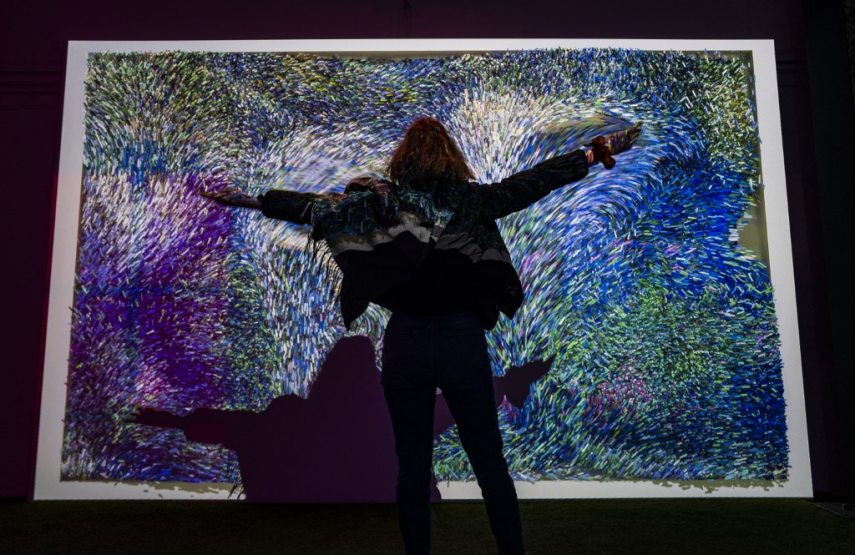 A visitor's movements are recorded by a motion sensor that translates them onto a pixel canvas inspired by the work of French painter Claude Monet (1840-1926), part of the "Monet's Garden" exhibition in Berlin on January 31, 2022. - The exhibition, which opened on January 12, 2022, mixes multimedia technology, installations and projections, combined with music, in a a bid to "bring the paintings to life in ways never before seen." (Photo by John MACDOUGALL / AFP) / RESTRICTED TO EDITORIAL USE - MANDATORY MENTION OF THE ARTIST UPON PUBLICATION - TO ILLUSTRATE THE EVENT AS SPECIFIED IN THE CAPTION