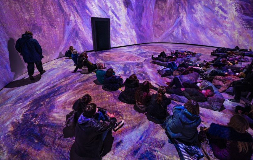 Visitors take in a 360 degree "immersive" animated projection inspired by the life and work of French painter Claude Monet (1840-1926), part of the "Monet's Garden" exhibition in Berlin on January 31, 2022. - The exhibition, which opened on January 12, 2022, mixes multimedia technology, installations and projections, combined with music, in a a bid to "bring the paintings to life in ways never before seen." (Photo by John MACDOUGALL / AFP) / RESTRICTED TO EDITORIAL USE - MANDATORY MENTION OF THE ARTIST UPON PUBLICATION - TO ILLUSTRATE THE EVENT AS SPECIFIED IN THE CAPTION