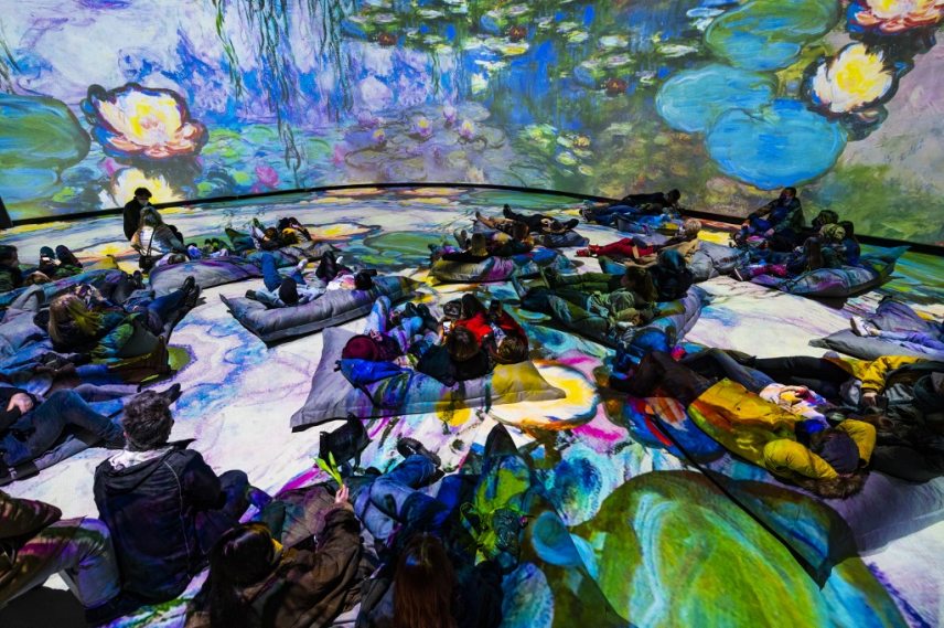 Visitors take in a 360 degree "immersive" animated projection inspired by the life and work of French painter Claude Monet (1840-1926), part of the "Monet's Garden" exhibition in Berlin on January 31, 2022. - The exhibition, which opened on January 12, 2022, mixes multimedia technology, installations and projections, combined with music, in a a bid to "bring the paintings to life in ways never before seen." (Photo by John MACDOUGALL / AFP) / RESTRICTED TO EDITORIAL USE - MANDATORY MENTION OF THE ARTIST UPON PUBLICATION - TO ILLUSTRATE THE EVENT AS SPECIFIED IN THE CAPTION