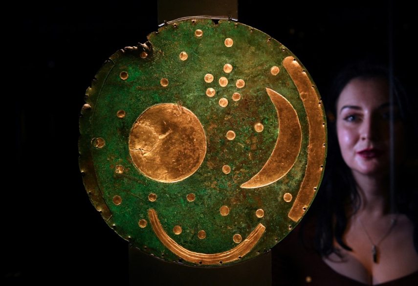 A museum employee looks at the oldest known sky-map made of gold and bronze
dated of 1600 BC and found in Nebra, Saxony-Anhalt, Germany, displayed during a press preview of the new exhibition "The World of Stonehenge" at the British Museum, in central London, on February 14, 2022. - The exhibition will run from February 17 until July 17, 2022. (Photo by Daniel LEAL / AFP)