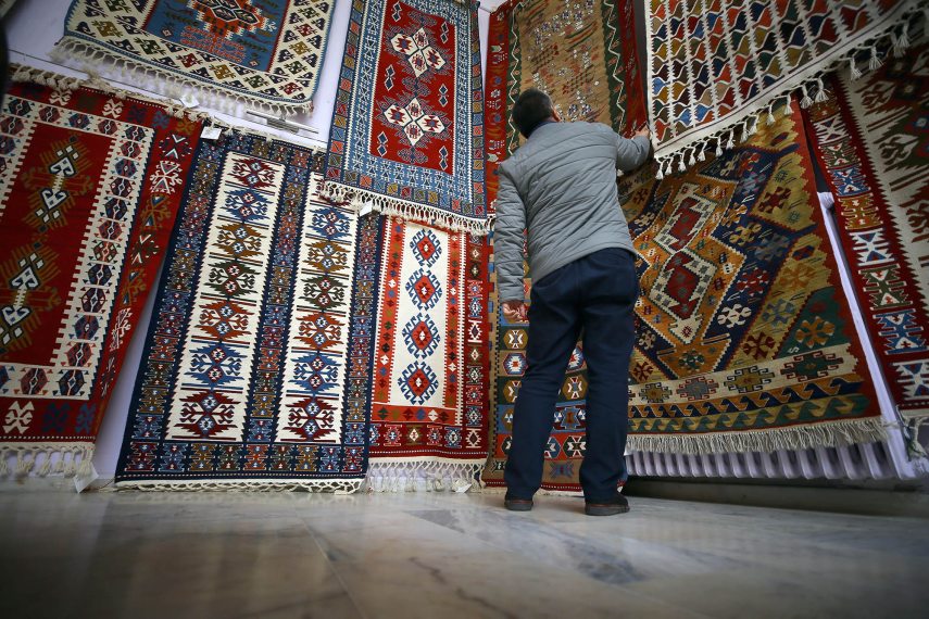 AFYONKARAHISAR, TURKEY - NOVEMBER 15 : A person views kilims hung on wall of a seller in Bayat district of Turkey's Afyonkarahisar province on November 15, 2018. A kilim is a traditionally produced flat tapestry-woven carpet or rug. Quite a process is required to prepare the yarn of the rugs. The wool collected from sheep are turned into yarns by hand. Yarns are given color with madder made of boiled tree roots, fruits or leaves. Once being boiled in caldrons the yarns are dried in the next step before the weaving starts. Kilims are special for gaining more vivid colors after washing. Tradition of kilim weaving has been around since the 6th century as they were special to Oghuz Turks' Bayat tribe. Abdullah Coskun / Anadolu Agency (Photo by Abdullah Coskun / ANADOLU AGENCY / Anadolu via AFP)