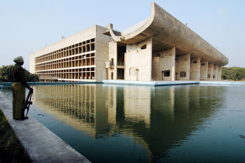 In this picture taken 19 November 2007, an Indian guard stands beside the Assembly Building of Chandigarh designed and built by Le Corbusier in Chandigarh. Thirty-five years ago, architect Jacques Sbriglio made a pilgrimage to India's only "planned city", Chandigarh, designed by France's Le Corbusier. Now he has brought here the biggest exhibit ever mounted in the country on the architectural icon, displaying more than 200 of his plans, models, paintings, photographs and other works. AFP PHOTO/Narinder NANU (Photo by NARINDER NANU / AFP)