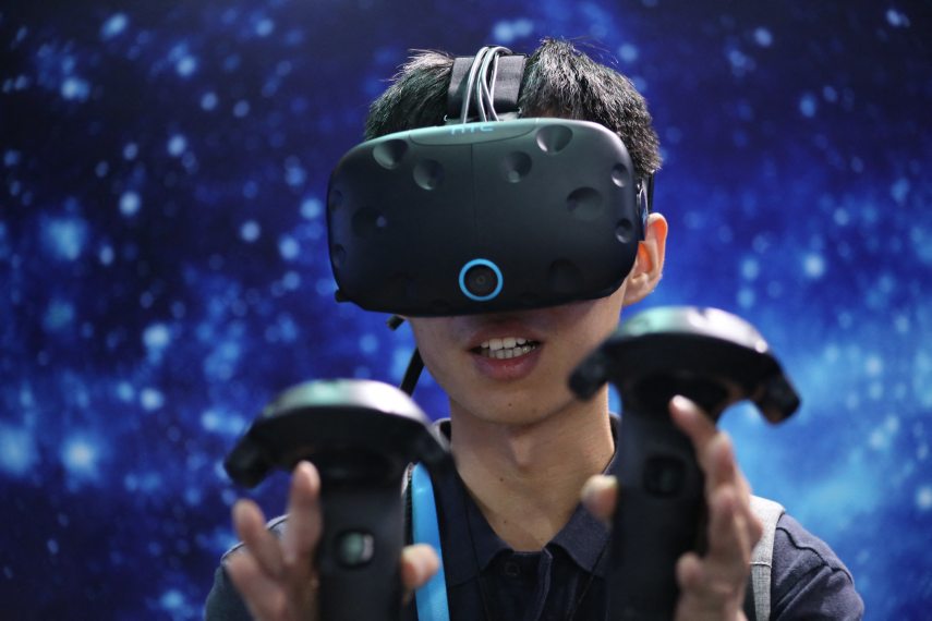 A visitor tries out a VR (Virtual Reality) device of HTC during the 2016 International Consumer Electronics Show Asia (CES Asia 2016) in Shanghai, China, 11 May 2016.
Hip-hop dancers, military marchers and daredevils in winged suits are bringing China's Internet titans into the world of virtual reality. These video stars have joined South Korean pop idols and animated fireflies as central players in a $1.1 billion global VR spending spree that's being fueled by Alibaba Group Holding Ltd., Tencent Holdings Ltd. and Baidu Inc. The three Web giants are using their money to employ a different perspective on the virtual-reality business than their overseas competitors. Instead of building headsets like Sony Corp., Facebook Inc. and HTC Corp., the Chinese companies are positioning themselves as middlemen: seeding dozens of startups and opening their platforms to developers of content and hardware while they wait for a dominant headset to emerge. The gambit means to capitalize on a domestic VR market expected to gro