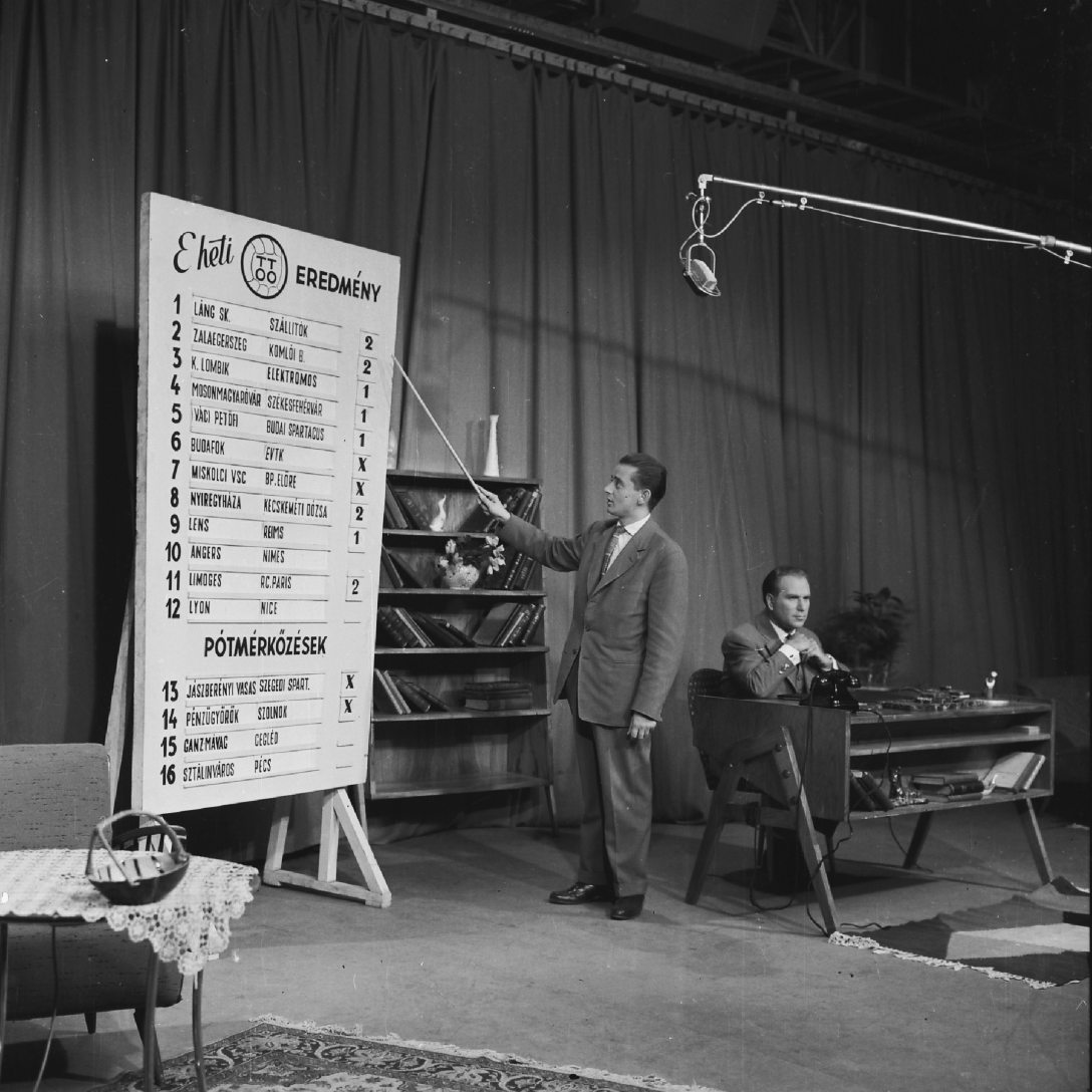 Vitár Róbert sportriporter a totó eredményeit ismerteti az MTV stúdiójában 1960-ban. A háttérben dr. Váradi György. Fotó: Fortepan / Rádió és Televízió Újság