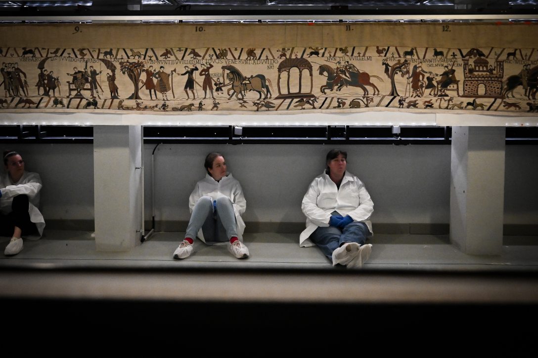Munkások és önkéntesek pihennek, mielőtt a Bayeux-i kárpitot ládába csomagolnák a British Museumba történő szállításra. Fotó: LOU BENOIST / POOL / AFP