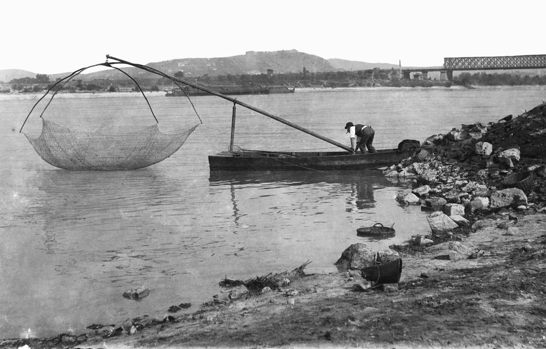 Halász a ferencvárosi Duna-partnál 1904-ben. Jobbra az Összekötő vasúti híd, háttérben a Gellért-hegy a Citadellával. Fotó: Fortepan / Deutsche Fotothek / Brück und Sohn
