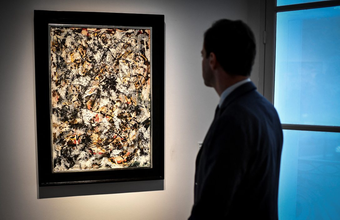Egy férfi Jackson Pollock amerikai művész „Kompozíció vörös ecsetvonásokkal” című festményét nézi, amely a Barney A. Ebsworth-gyűjtemény része. Fotó:  Stephane de Sakutin / AFP