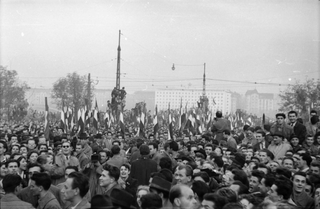 Magyarország, Budapest II. Bem József tér, tüntetés 1956. október 23-án a Bem szobornál. Háttérben az ÁVH egykori, ekkor már a BM-hez tartozó épülete, a mai Képviselői Irodaház ("Fehér Ház"). Fotó: Fortepan / Faragó György